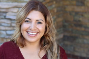 woman smiling in front of brick wall