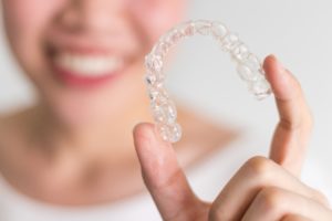 Woman holding aligner for Invisalign in Southlake