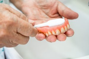 Pair of hands holding dentures in Southlake over sink