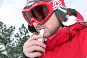 Man wearing ski goggles, applying lip balm