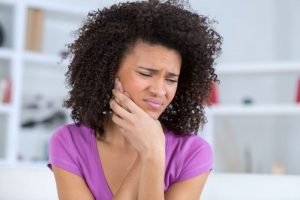 Woman holding hand to her face, experiencing pain