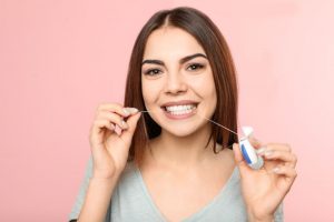 Smiling woman holding floss between her teeth