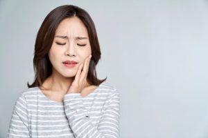 Woman with toothache, touching her face and wearing pained expression