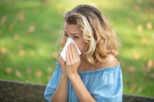 Woman sitting outside, blowing her nose