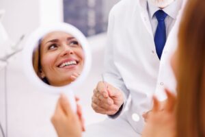 Dental patient’s smile reflected in hand mirror 