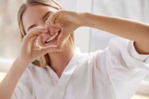 Woman making a heart shape with her hands, showing off her smile