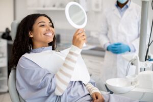 Happy dental patient smiling at herself in mirror