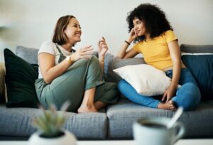 Two friends sitting on sofa, conversing 