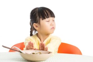 Child pushing away her plate of food 